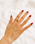Gold-plated chain ring worn on hand against white fabric