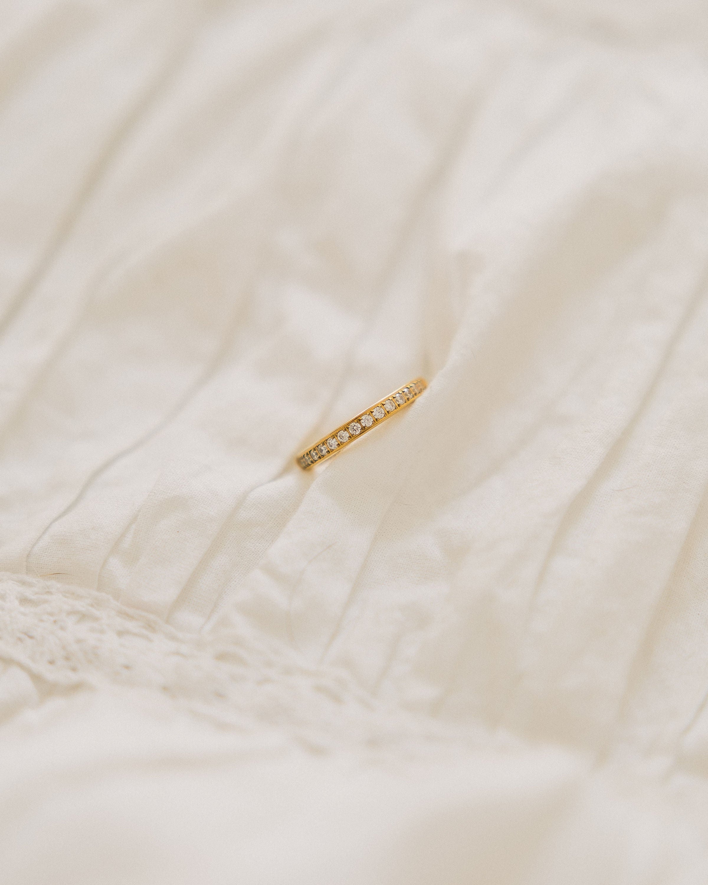 Crystal band ring gold-plated with rhinestones on white fabric