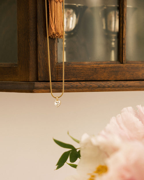 Crystal Heart Necklace worn by model in cream lace top showing heart zircon pendant on snake chain