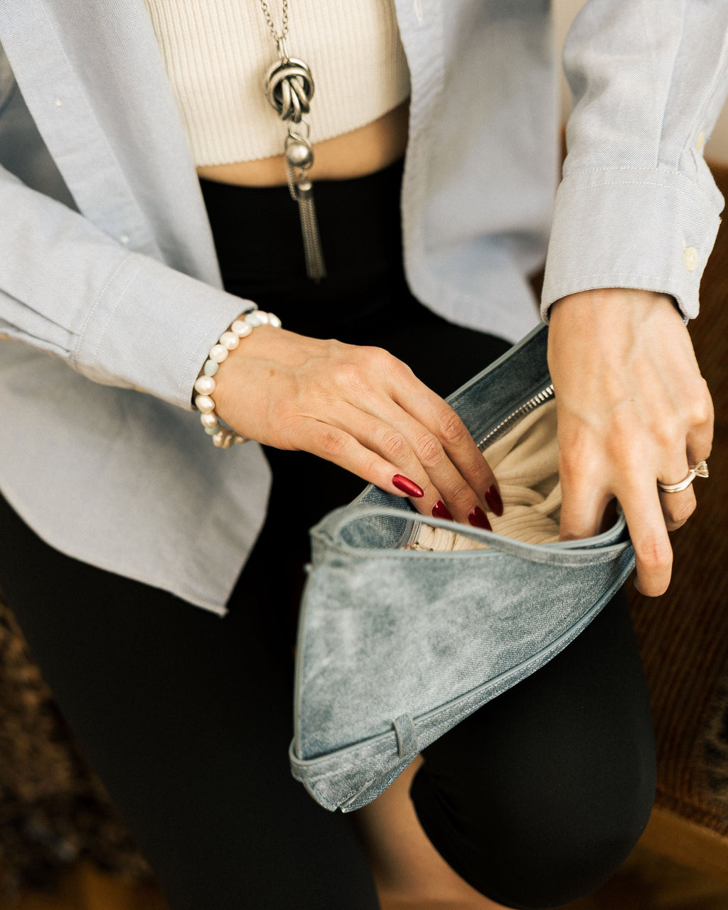 Denim Effect Baguette Bag flat lay on white bedding with silver necklace and pearl bracelet