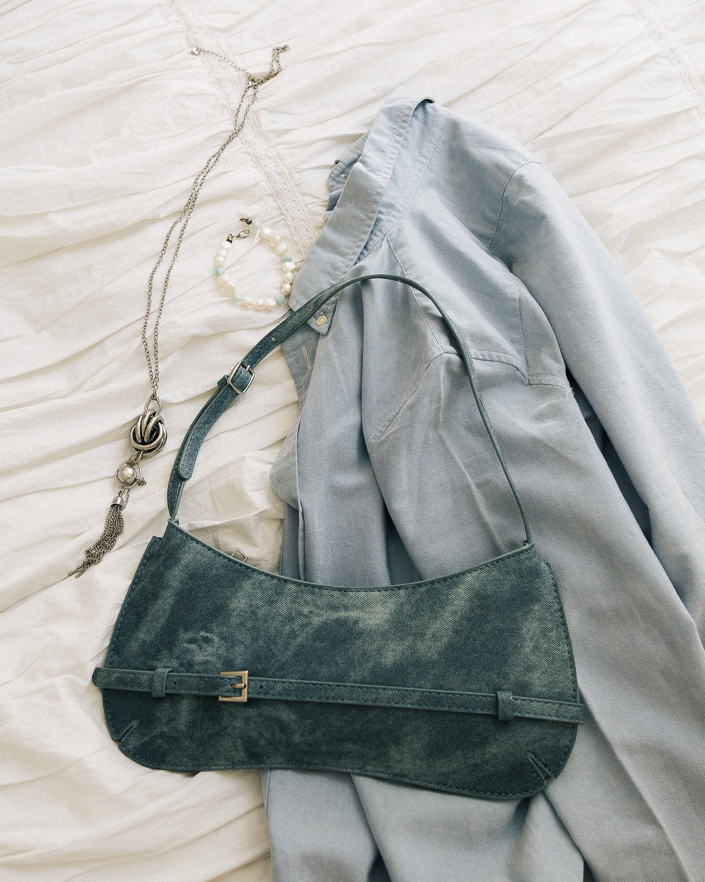 Denim Effect Baguette Bag close-up on white linen showing buckle detail