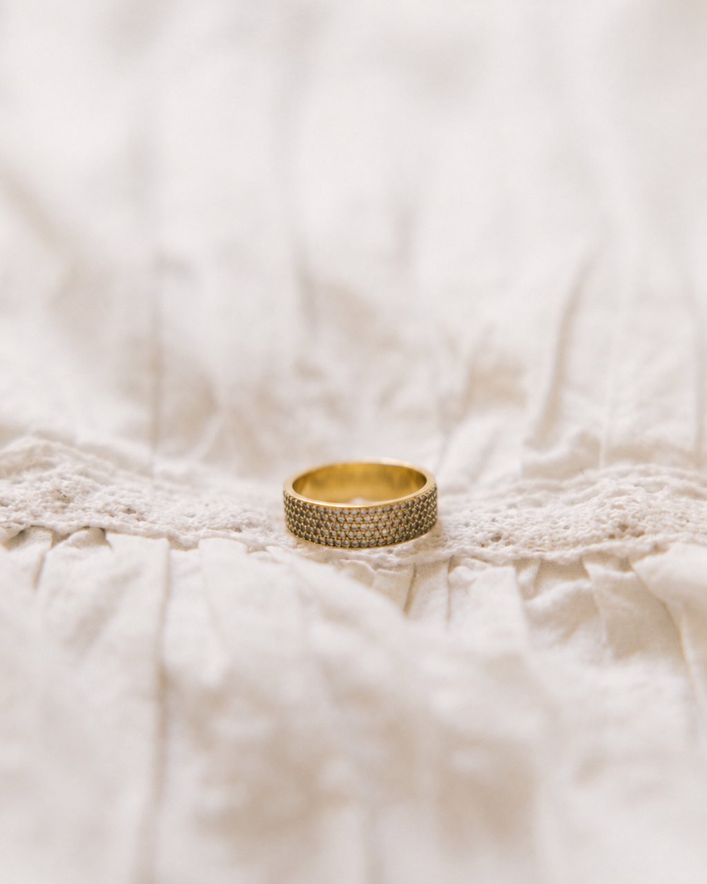 Pavé ring gold-plated with rhinestones on white lace fabric