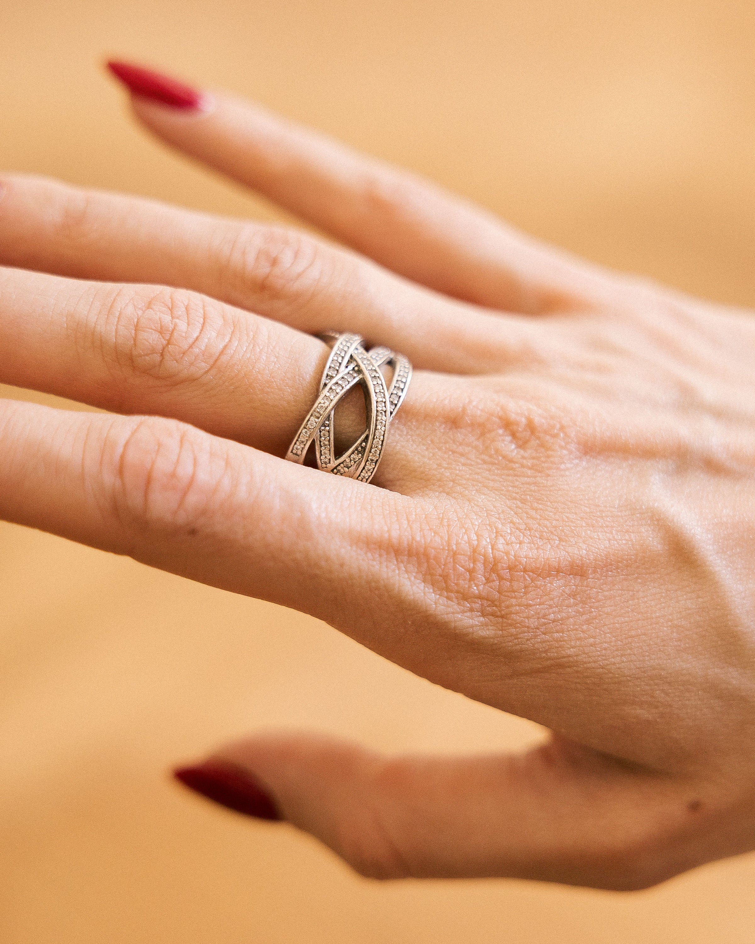Silver crossover ring with rhinestone accents on hand