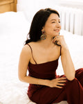 Vintage Baroque Statement Earrings worn by model in burgundy dress on white bed
