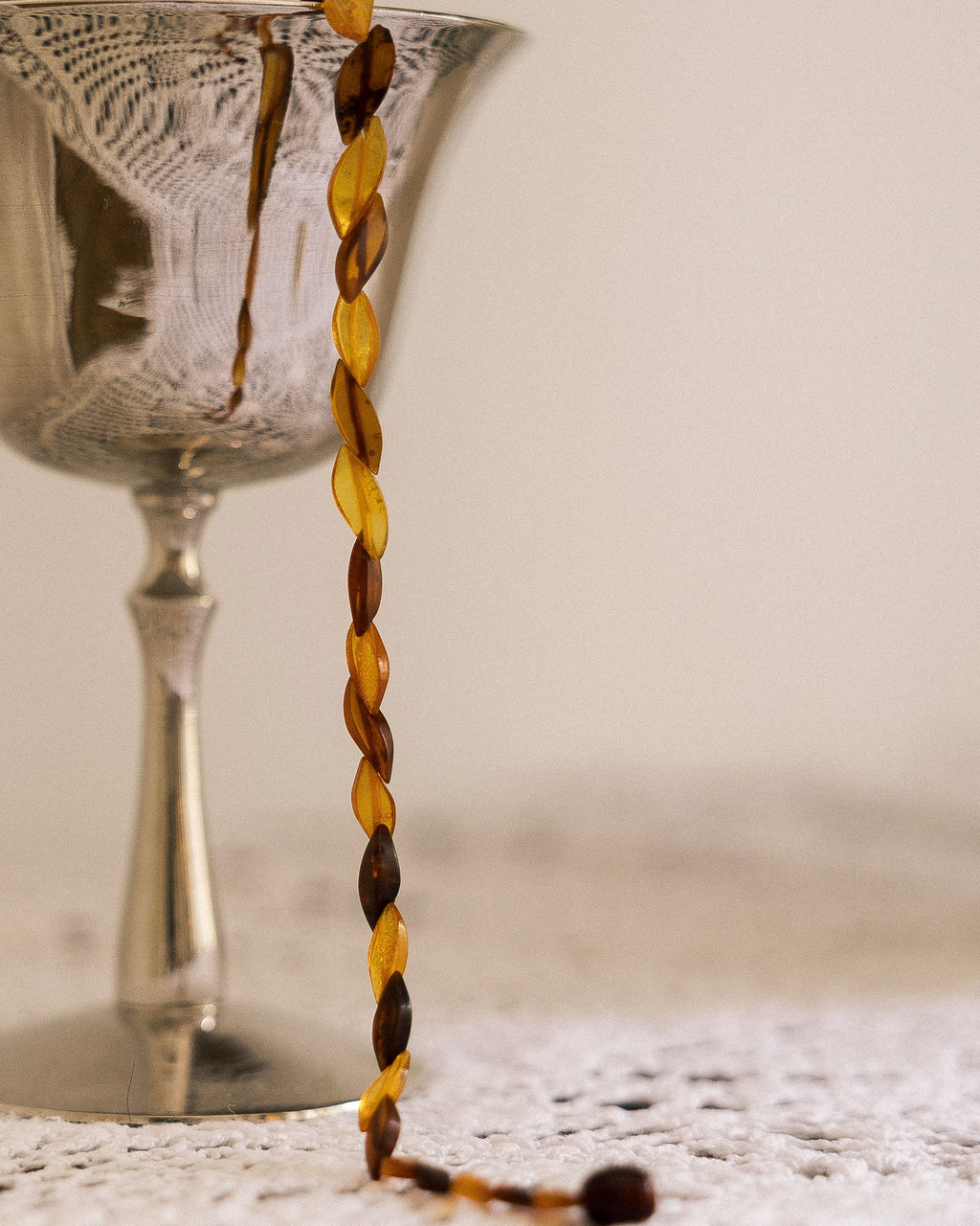 Vintage Honey Toned Necklace draped over silver glass on lace cloth