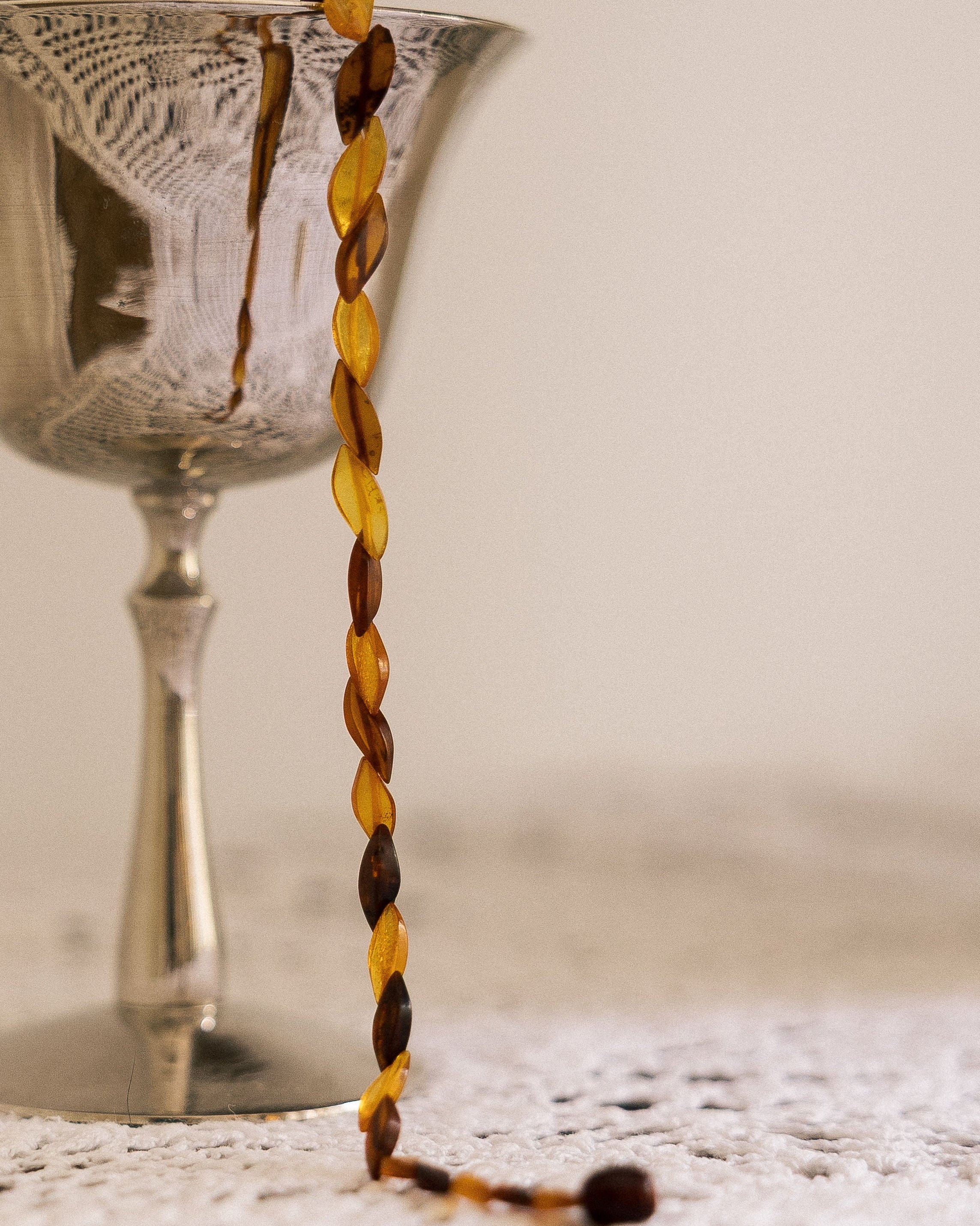 Vintage Honey Toned Necklace draped over silver glass on lace cloth